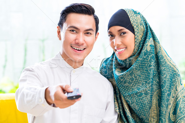 Asian Muslim Couple switching TV with remote control Stock photo © Kzenon