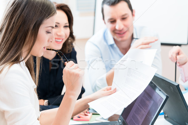 Women and men in office reading documents Stock photo © Kzenon