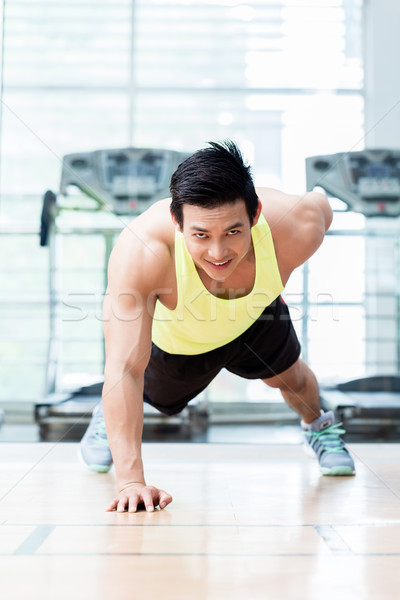 Muscular young man doing one armed pushups in gym Stock photo © Kzenon