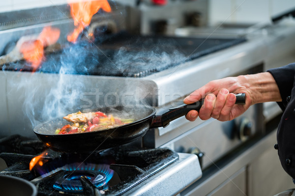 Chef doing flambe to food in pan with alcohol Stock photo © Kzenon