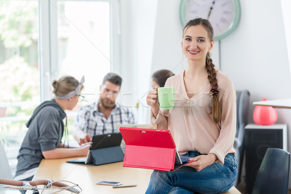 Portrait of a confident young woman sitting on the desk of a co- Stock photo © Kzenon