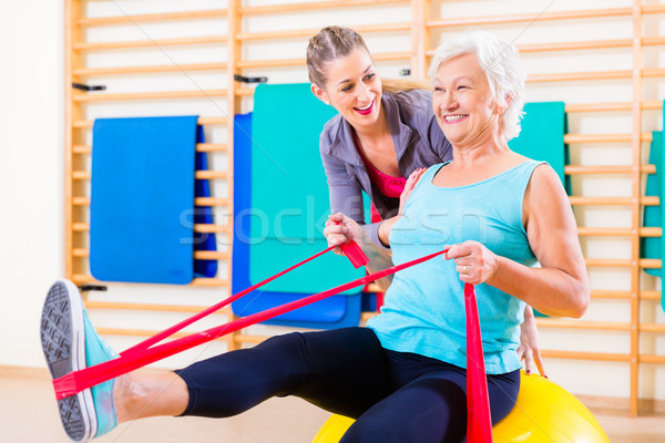 Senior woman with stretch band at fitness Stock photo © Kzenon