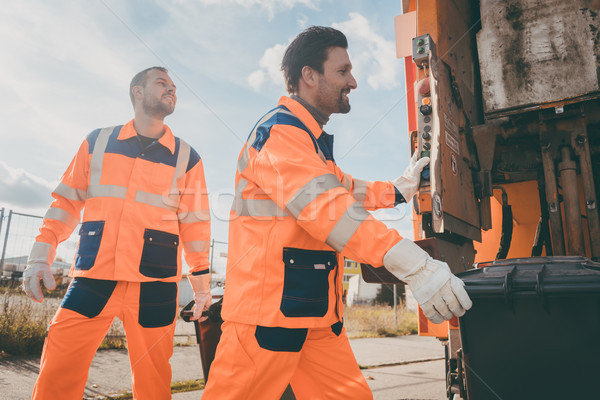 Two garbagemen working together on emptying dustbins  Stock photo © Kzenon