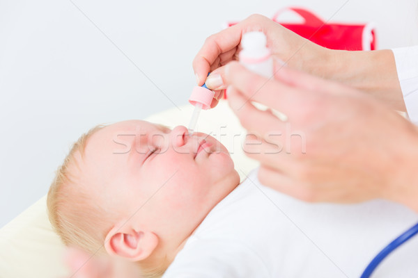 Pediatrician clearing the nose of a baby by applying saline solution Stock photo © Kzenon