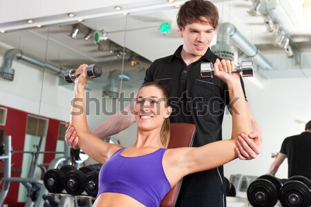 Handsome personal trainer guiding a beautiful woman at a modern fitness Stock photo © Kzenon