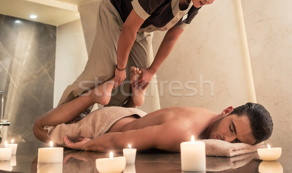 Thai massage practitioner massaging man through stretching techniques Stock photo © Kzenon