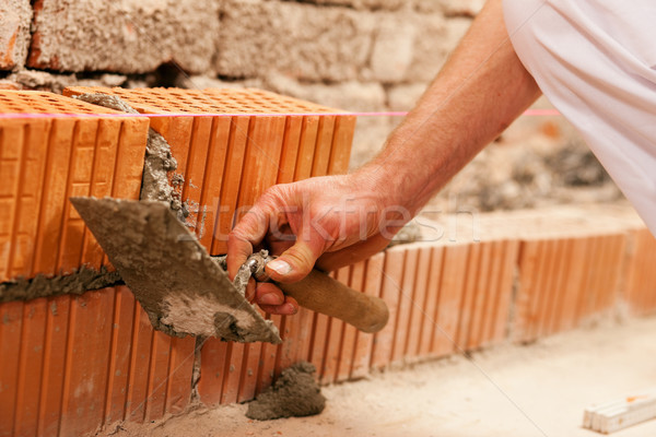 bricklayer making wall with brick and grout Stock photo © Kzenon