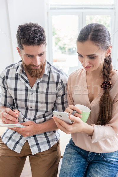 Two co-workers smiling while watching a video on the mobile in a Stock photo © Kzenon