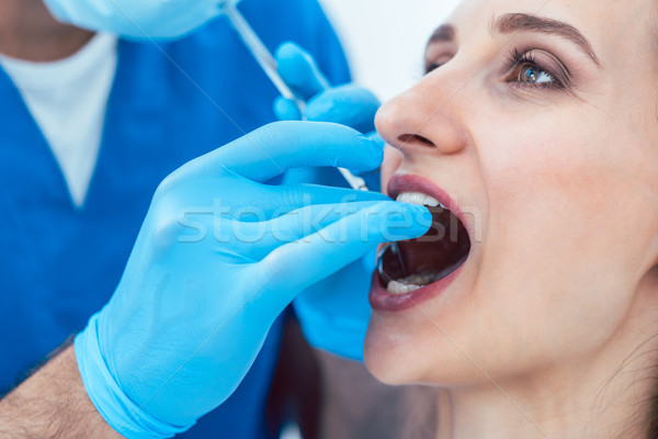 Close-up of the hands of a dentist cleaning the teeth of a young woman Stock photo © Kzenon
