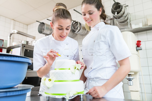 Two pastry bakers decorating large cake Stock photo © Kzenon