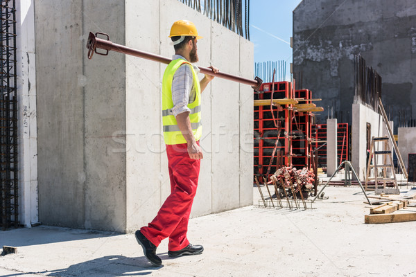 Blue-collar worker carrying a heavy metallic bar during work Stock photo © Kzenon