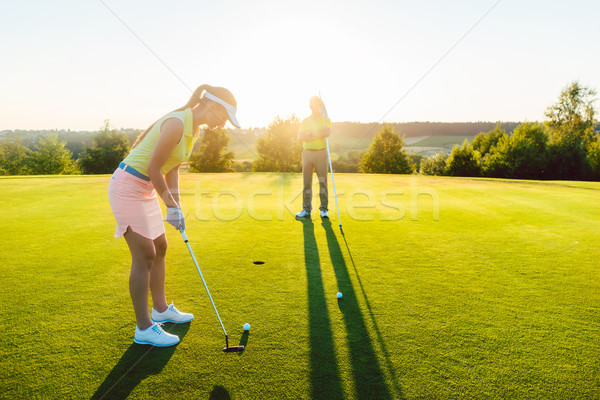 Female golf player ready to hit the ball into the cup Stock photo © Kzenon