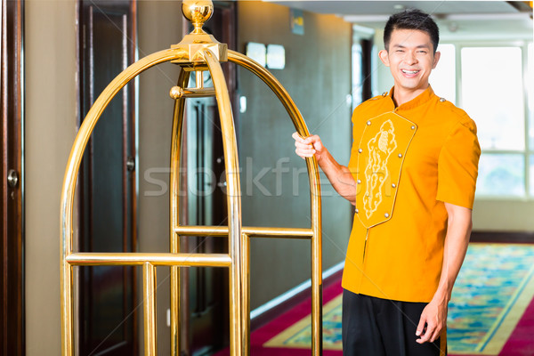 Asian bell boy or porter bringing suitcase to hotel room Stock photo © Kzenon