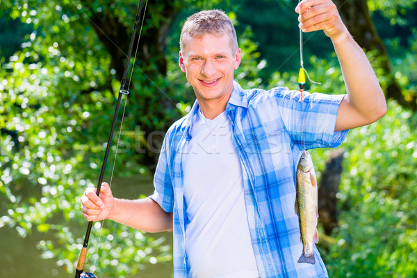 Sport fisherman showing catch dangling from fishing rod Stock photo © Kzenon