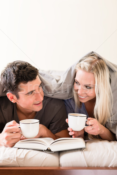 Young couple reading a book together in bed Stock photo © Kzenon