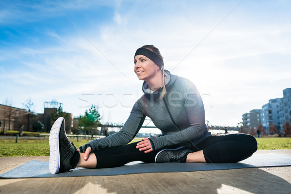 Young beautiful woman smiling while sitting down in a stretching Stock photo © Kzenon