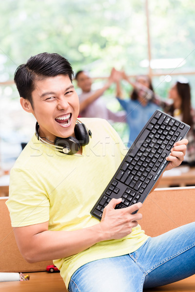 Young Chinese employee happy for his successful work on computer Stock photo © Kzenon