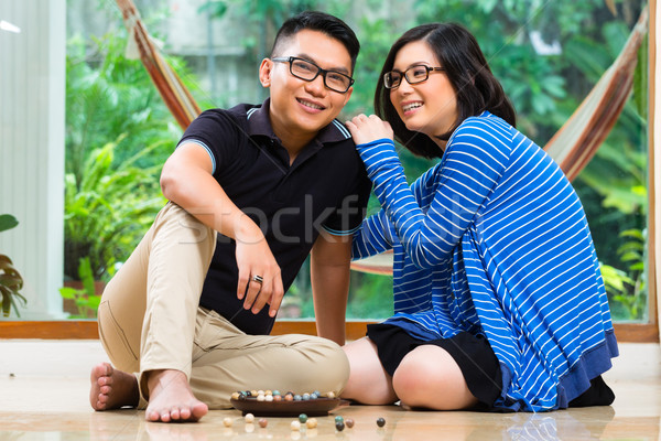 Asian couple at home playing with marbles Stock photo © Kzenon