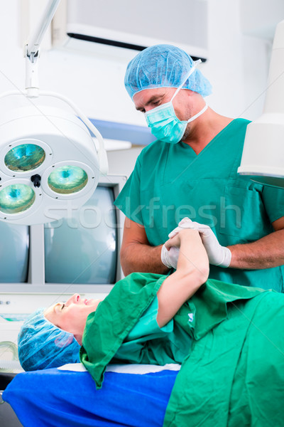 Surgeon in operating room holding hand of patient Stock photo © Kzenon