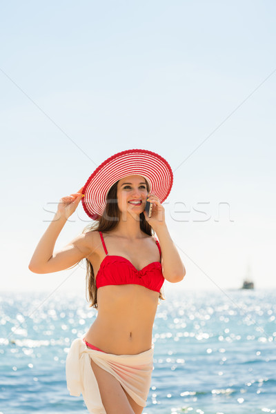 Fashionable fit young woman talking on mobile phone on the beach Stock photo © Kzenon