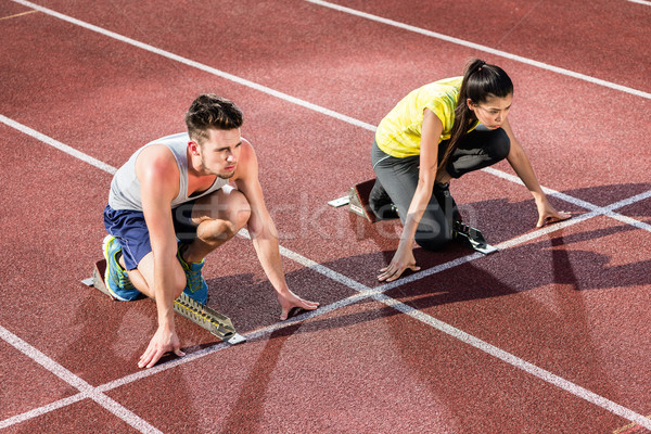 Male and female athlete in starting position at starting block Stock photo © Kzenon