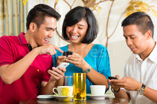Asian people having fun with mobile phone Stock photo © Kzenon