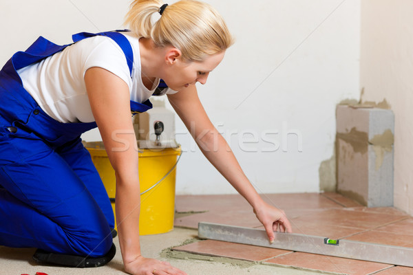 Female tiler tiling tiles on the floor Stock photo © Kzenon