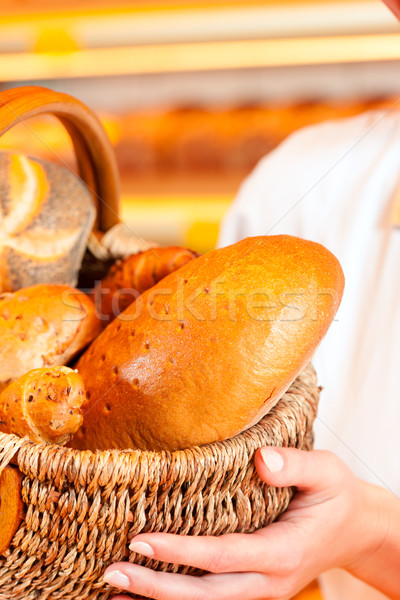 Female baker in bakery selling bread by basket  Stock photo © Kzenon
