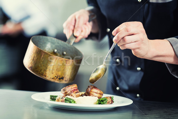 Chef pouring sauce on dish in restaurant kitchen Stock photo © Kzenon