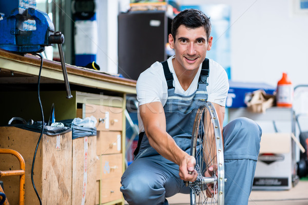 Man as bicycle mechanic working in workshop Stock photo © Kzenon