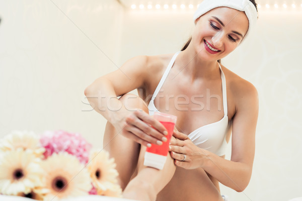 Fit woman waxing her legs with a portable roll-on depilatory wax Stock photo © Kzenon