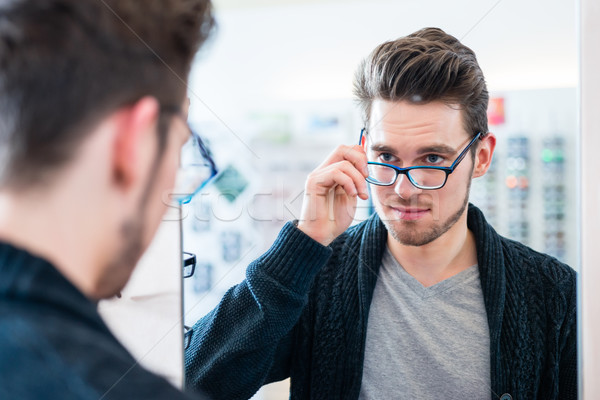Man testing glasses in optician shop mirror Stock photo © Kzenon