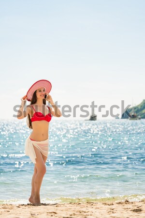 Beautiful young woman wearing a trendy striped hat at the beach Stock photo © Kzenon