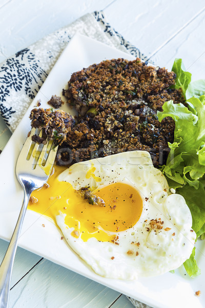 healthy meal of black bean cake with mixed greens and a frie 