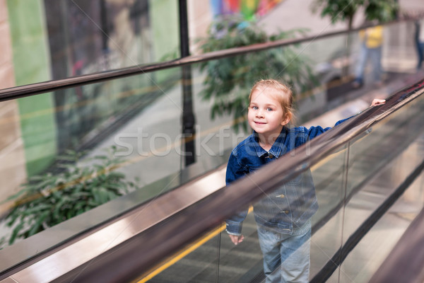 Cute little child in shopping center standing on moving escalator Stock photo © Len44ik