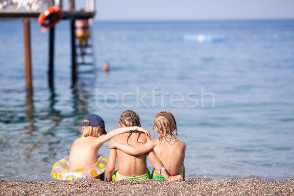 Three children sitting on a beach Stock photo © Len44ik
