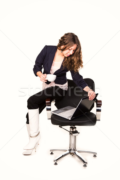 Beautiful businesswoman with cup of coffee in a chair with lapto Stock photo © Len44ik