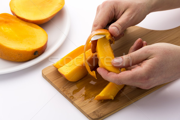 Hands Separating Mango Fruit Flesh From Its Skin Stock photo © leowolfert