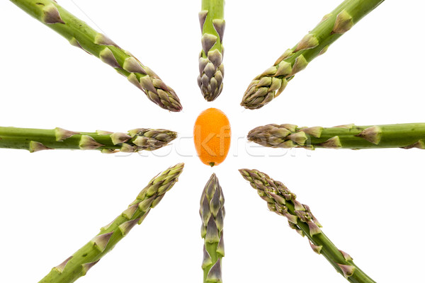 Eight Asparagus Spears Aiming at One Kumquat Stock photo © leowolfert