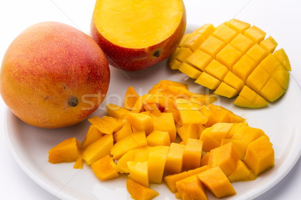 Heap Of Juicy Mango Cubes And Whole Fruit On Plate Stock photo © leowolfert