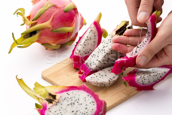 Hands Removing Pulp From A Pitaya Fruit Wedge Stock photo © leowolfert