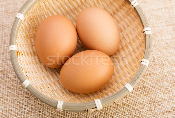 Brown egg in basket over linen background Stock photo © leungchopan