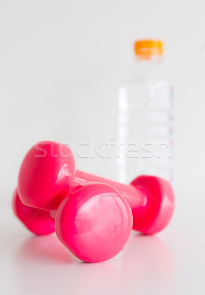 Two pink glossy dumbbell and water bottle Stock photo © leungchopan