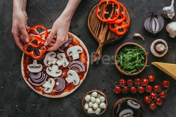 cropped shot of woman spreading bell pepper slices onto pizza on concrete table Stock photo © LightFieldStudios