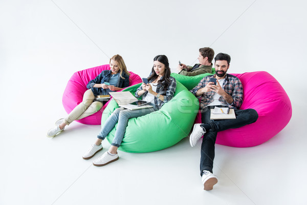 students sitting on beanbag chairs and studying and using smartphones in studio on white  Stock photo © LightFieldStudios