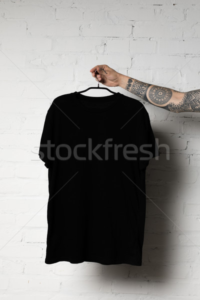Schwarz tshirt erschossen Mann halten Kleiderbügel Stock foto © LightFieldStudios