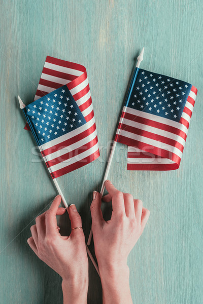 partial view of woman holding american flags in hands on blue wooden tabletop, presidents day concep Stock photo © LightFieldStudios