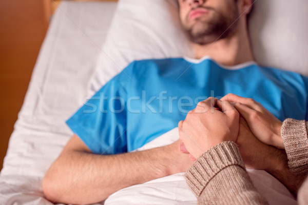 Doente homem hospital ver mulher de mãos dadas Foto stock © LightFieldStudios