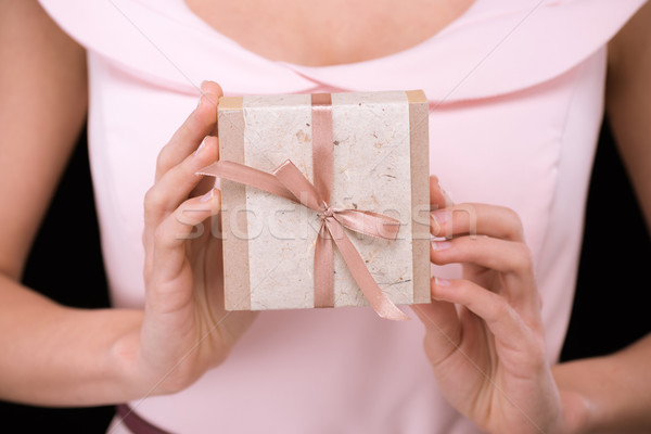 Close-up partial view of woman in pink dress holding gift box on black, international womens day con Stock photo © LightFieldStudios