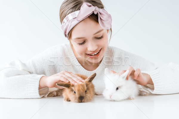 beautiful happy girl playing with adorable furry rabbits on white Stock photo © LightFieldStudios